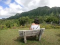 Young traveler female tourist sitting relaxing on the bench in front of mountains looking aside enjoying panoramic mountain in