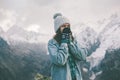 Young traveler girl in gloves standing over mountain peaks and warming cold hands