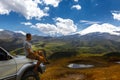 Young Traveler Man Sits On Car And Enjoys View Of Mountains In Summer. Elbrus Region, North Caucasus, Russia