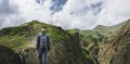 Young Traveler Man Standing On Top Of Cliff In Mountains And Enjoying View Of Nature, Rear View Royalty Free Stock Photo