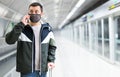 Young traveler in mask talking on phone on subway platform Royalty Free Stock Photo