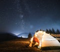 Camping with illuminated tent in night mountains. Royalty Free Stock Photo