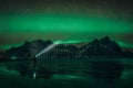 Young traveler standin in front of Vestrahorn Stockknes mountain range with aurora borealis and reflection at the beach