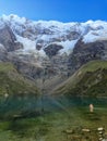 A young traveler takes a cold dip in the frigid waters of the glacial Humantay Lake, hidden beside Salkantay Mountain deep in