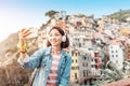 Traveler tourist woman taking selfie on her smartphone in famous old italian village Riomaggiore, Cinque Terre, Italy Royalty Free Stock Photo