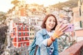 traveler tourist woman taking selfie on her smartphone in famous old italian village Riomaggiore, Cinque Terre, Italy Royalty Free Stock Photo