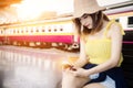 Young traveler woman holding mobile phone in hand waiting on platform at railway station waiting for train Royalty Free Stock Photo