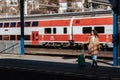 Young traveler woman with luggage waiting for train at train station platform.Train in the background. Royalty Free Stock Photo