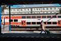 Young traveler woman with luggage waiting for train at train station platform.Train in the background. Royalty Free Stock Photo