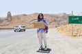 Young traveler woman stand on side of road hitchhike with sign to Shiraz and thumbs up with smile in Iran .Solo safe travel in