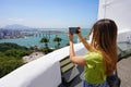 Young traveler woman takes picture with her smartphone of Vitoria city from Penha Convent in Vila Velha, Espirito Santo, Brazil Royalty Free Stock Photo