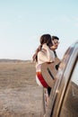 Young travelers lovers having fun with the guitar on top of jeep 4x4 car. Couple making a wanderlust vacation at summer
