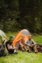 Young travelers resting in tents while hiking in green forest