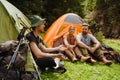 Young travelers resting in tents while hiking in green forest