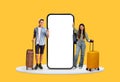 Young travelers with suitcases next to large blank phone