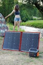 Woman at camping uses solar panel to generate electricity Royalty Free Stock Photo