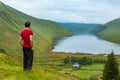 A young traveller man observing a lake in a deep valley covered