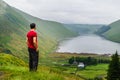 A young traveller man observing a lake in a deep valley covered