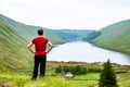 A young traveller man observing a lake in a deep valley covered