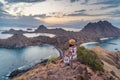 Young traveller sitting and relaxing on top of Padar island at sunset, Komodo national park in Indonesia