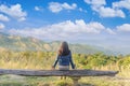 Young traveller woman sitting on wood bench, relaxing and enjoying the panoramic view of on the morning