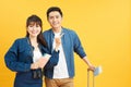 Young travelling couple with suitcases pointing somewhere isolated on yellow Royalty Free Stock Photo