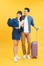 Young travelling couple with suitcases pointing somewhere  on yellow Royalty Free Stock Photo