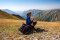 Young trekker man resting and playing guitar in rocky pass with mountain top wiews in high mountains. Young men and women hiking