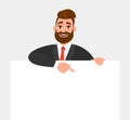 Young trendy businessman showing blank white poster and pointing finger. Happy hipster person holding empty banner. Royalty Free Stock Photo