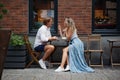 Young trendy Couple Talking and smile at Coffee Shop on street of city. Stylish man and woman full length portrait at restaurant Royalty Free Stock Photo