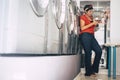 Young trendy fashion brunette use phone and wait in a laundry mat service store in the city - washing clothes activity in Royalty Free Stock Photo