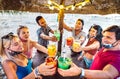 Young trendy friends toasting at beach cocktail bar chiringuito with face mask - New normal summer concept with people having fun Royalty Free Stock Photo