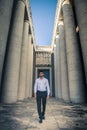 Young trendy man walking through the ancient columns of a historic building. Royalty Free Stock Photo