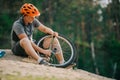 young trial biker pumping wheel of bicycle outdoors while sitting