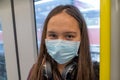 Young tween girl wearing surgical mask on subway