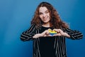 young Ukrainian curly hair woman smiling and showing a heart shape with hands with flag Ukraine