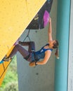 Young Ukrainian lady athlete climbing yellow and blue wall on the EU Cup competition in Arko, Italy