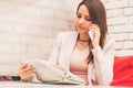 Young woman reading a newspaper and talking on mobile phone Royalty Free Stock Photo