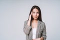 Young unhappy asian business woman with long hair in suit and jeans holding her hands on head on grey background Royalty Free Stock Photo