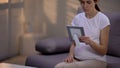 Young unhappy pregnant widow looking at photo in frame, suffering loneliness