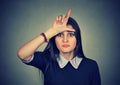 Young unhappy woman giving loser sign on forehead Royalty Free Stock Photo