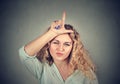 Young unhappy woman giving loser sign on forehead Royalty Free Stock Photo