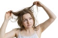 Young unhappy woman is looking at her damaged and dry hair. Isolated on white background