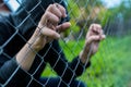 Young unidentifiable teenage boy holding the wired garden at the correctional institute, conceptual image of juvenile delinquency,