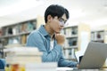 Young university student using laptop for online learning, searching and learning at library. Royalty Free Stock Photo