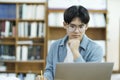 Young university student using laptop for online learning, searching and learning at library. Royalty Free Stock Photo