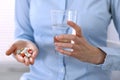 Young unknown woman holding pills and glass of water, closeup of hands. Medicine and healthcare concept Royalty Free Stock Photo