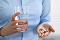 Young unknown woman holding pills and glass of water, closeup of hands. Medicine and healthcare concept Royalty Free Stock Photo