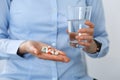 Young unknown woman holding pills and glass of water, closeup of hands.  Medicine and healthcare concept Royalty Free Stock Photo