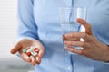 Young unknown woman holding pills and glass of water, closeup of hands.  Medicine and healthcare concept Royalty Free Stock Photo